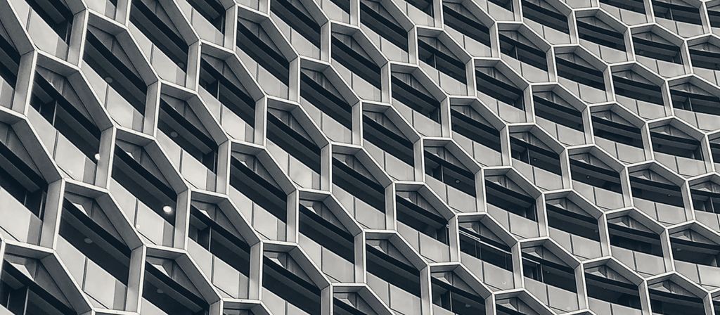 A glass tower facade patterned with hexagonal frames